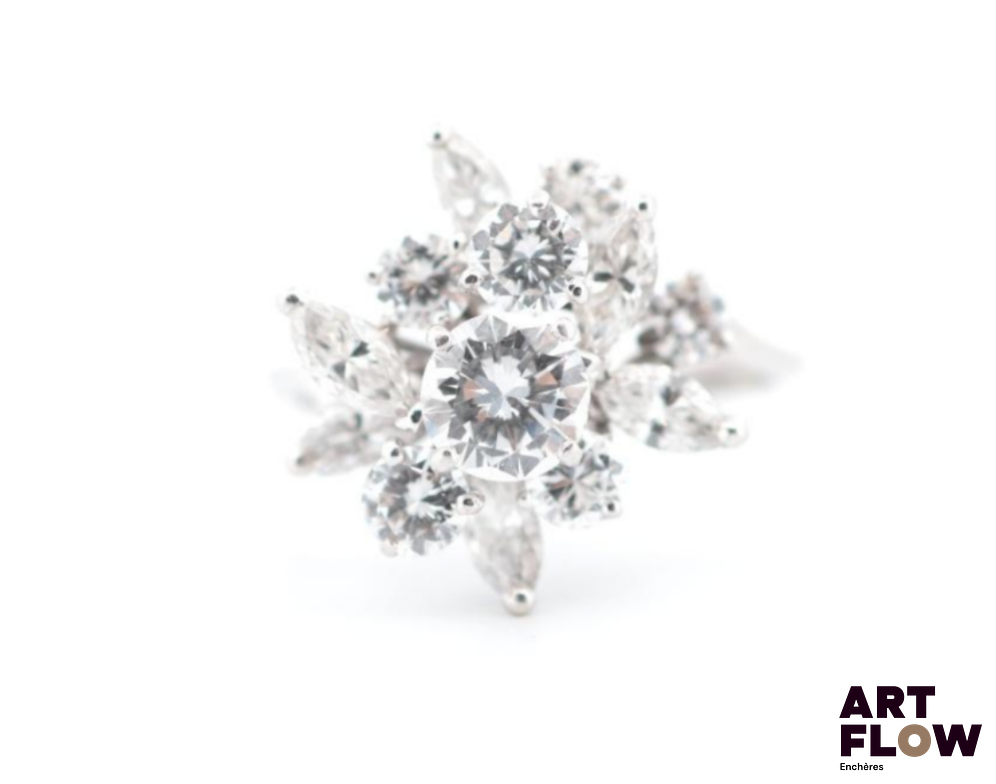 Bague en or blanc 750‰, en forme de bouquet de feuilles stylisées, entièrement sertie de diamants ; le centre orné d’un diamant taille brillant de 0.65 carat environ de qualité estimée F VS (légère égrisure), et entouré de 6 diamants taille brillant entre 0.11 carat et 0.25 carat environ chaque et de 6 diamants taille navette de 0.15 carat chaque sur différents niveaux afin de créer une ravissante perspective ; le tout pour un poids total de 1.85 carat environ. La monture en fils, la structure de la bague, la forme et la qualité des pierres utilisées indiquent un travail fort probablement français des années 1970. (Un fil dessoudé, traces d’anciennes soudures) Diamants : 2.50 carats environ Poids : 4.45 g Tour de doigt : 56