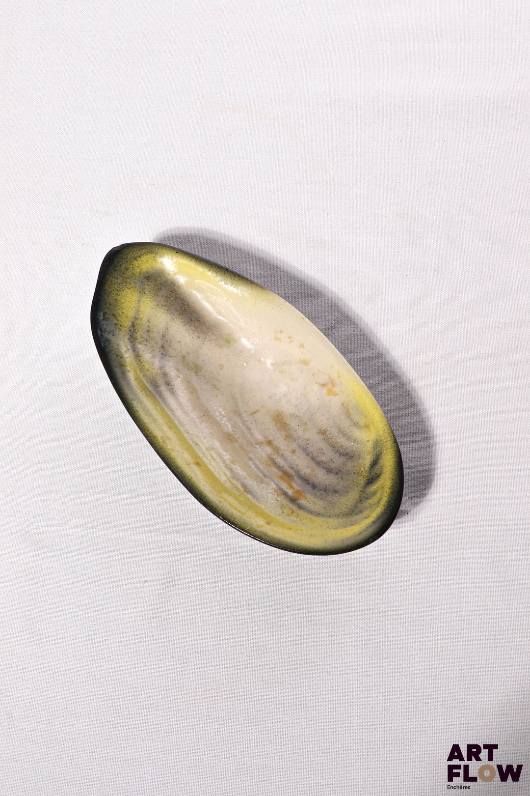 POL CHAMBOST (1906-1983) Coupe 1026 "Coquillage" en faience émaillée à couverte polychrome, l'intérieur dans les tons jaune et nacre, l'extérieur noir. Incisé "1056" et monogrammé "PC". 19,5 x 10 x 4 cm Bibliographie : Philippe Chambost, "Pol Chambost, Sculpteur-Céramiste 1906-1983", Somogy Editions d'Art, Paris, 2006, modèle similaire p. 80