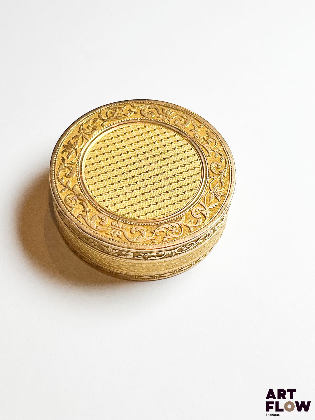 Pilulier en or jaune 750/°°, de forme circulaire, à décor central imitant la vanerie, dans un entourage de frise feuillagée. Poids : 24,85 gr