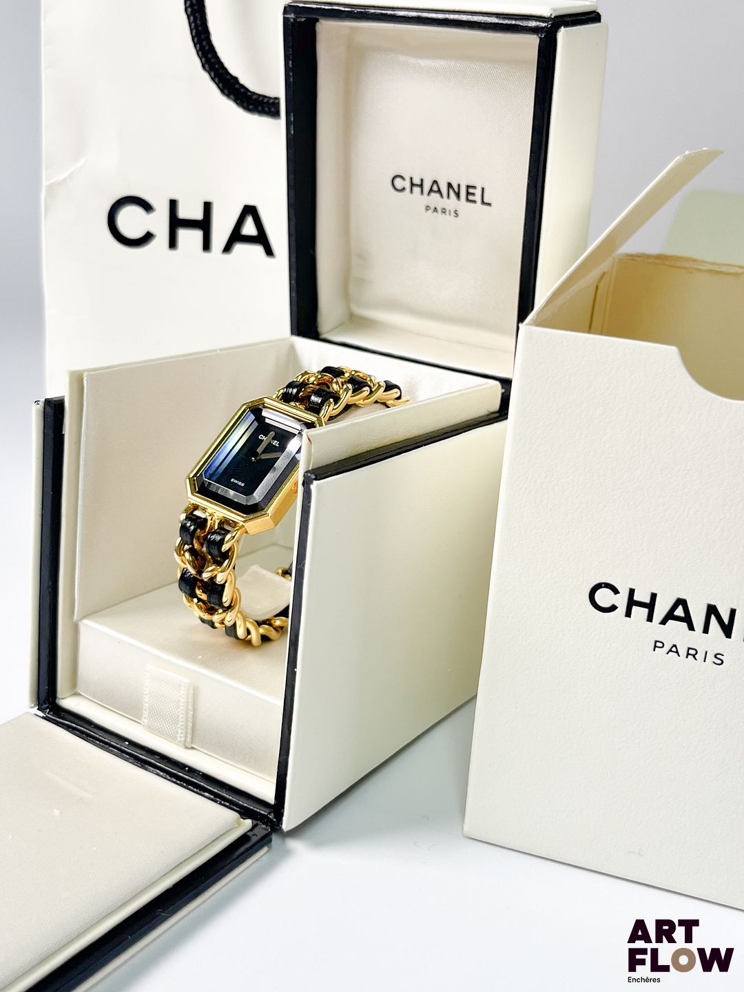 CHANEL Modèle "Ma Première" Montre bracelet femme en plaqué or, à mouvement à quartz, le boîtier octogonale à cadran à fond noir, index muets, aiguilles dorées, verre facetté, le bracelet en cuir noir et métal doré Diamètre 26 x 20 mm Longueur du bracelet : 13,5 cm env. Référence H0001 Bon état général Pile à remplacer, mécanisme non garanti. La Chanel Première est lancée en 1987 par la maison Chanel, marquant son entrée dans l’horlogerie féminine. Inspirée du flacon du Chanel No. 5 et de la place Place Vendôme, elle se distingue par son boîtier octogonal et son bracelet chaîne élégant.