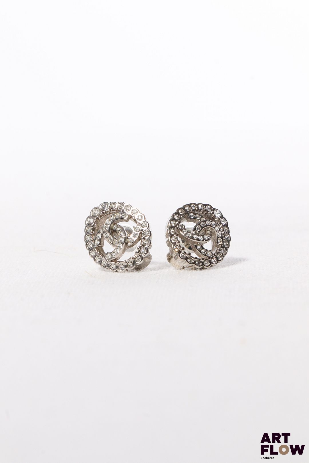 CHANEL Boucles d’oreille ovales en métal argenté et strass, prenant la forme des deux C entrelacés. Siglées au dos sur plaque. 1,5 x 1 cm env. Etat proche du neuf