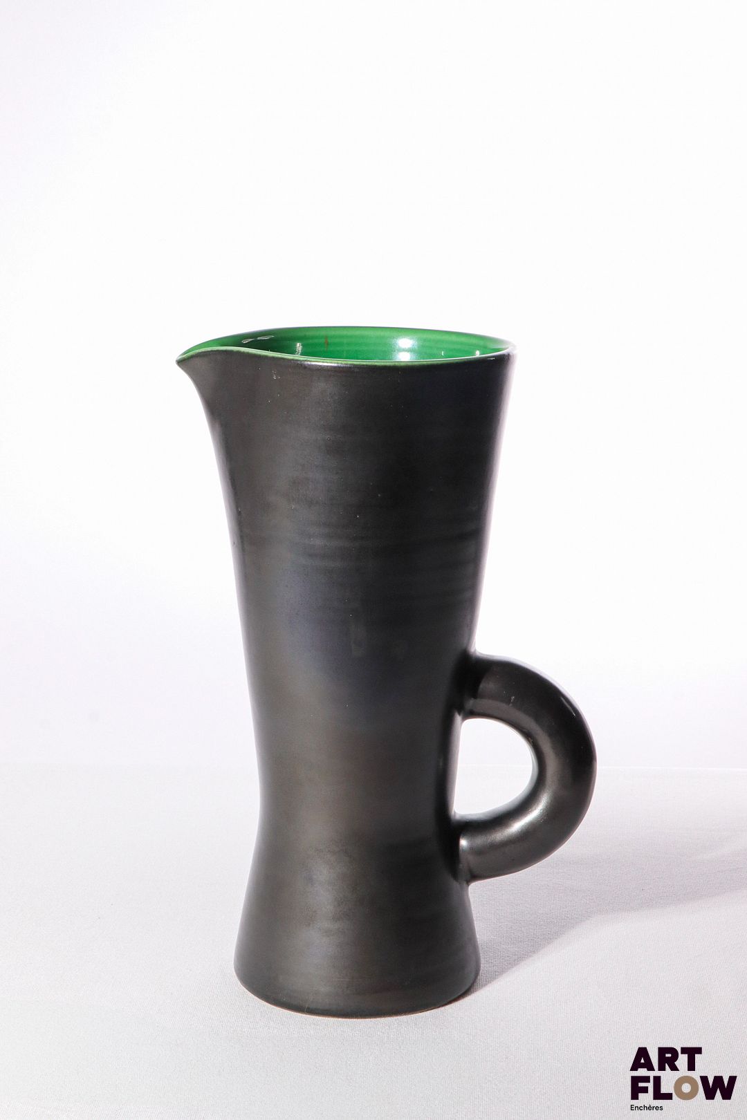 POL CHAMBOST (1906-1983) Pichet 860 de forme diabolo en faience émaillée à couverte noire à l'extérieure, verte à l'intérieur. Incisé au revers "Poterie Pol Chambost, 860", et tampon "Made in France" 26,5 x 15 x 12 cm Bibliographie : Philippe Chambost, "Pol Chambost, Sculpteur-Céramiste 1906-1983", Somogy Editions d'Art, Paris, 2006, modèle similaire p. 76