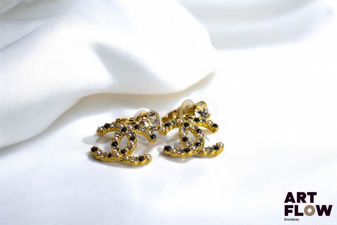 Chanel Paire de boucles d'oreilles dormeuses en métal doré ornées d'un strass, retenant le double C entrelacé en pampille. Très bon état