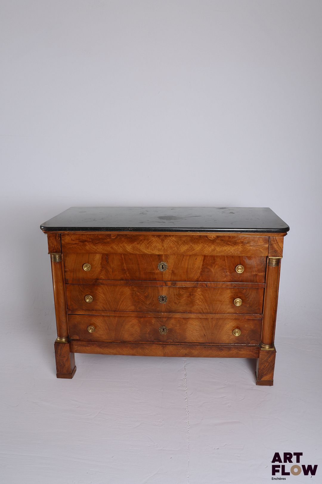 Commode en acajou et placage d'acajou ouvrant a quatre tiroirs à traverses, à décor de colonnes détachées, ornementation de bronze doré et dessus de marbre noir. Époque Empire. 91 x 130 x 60 cm Bon état général malgré de petits accidents et restaurations (notamment fentes réparées sur les côtés) Facture de réparation et nettoyage de mai 2011.