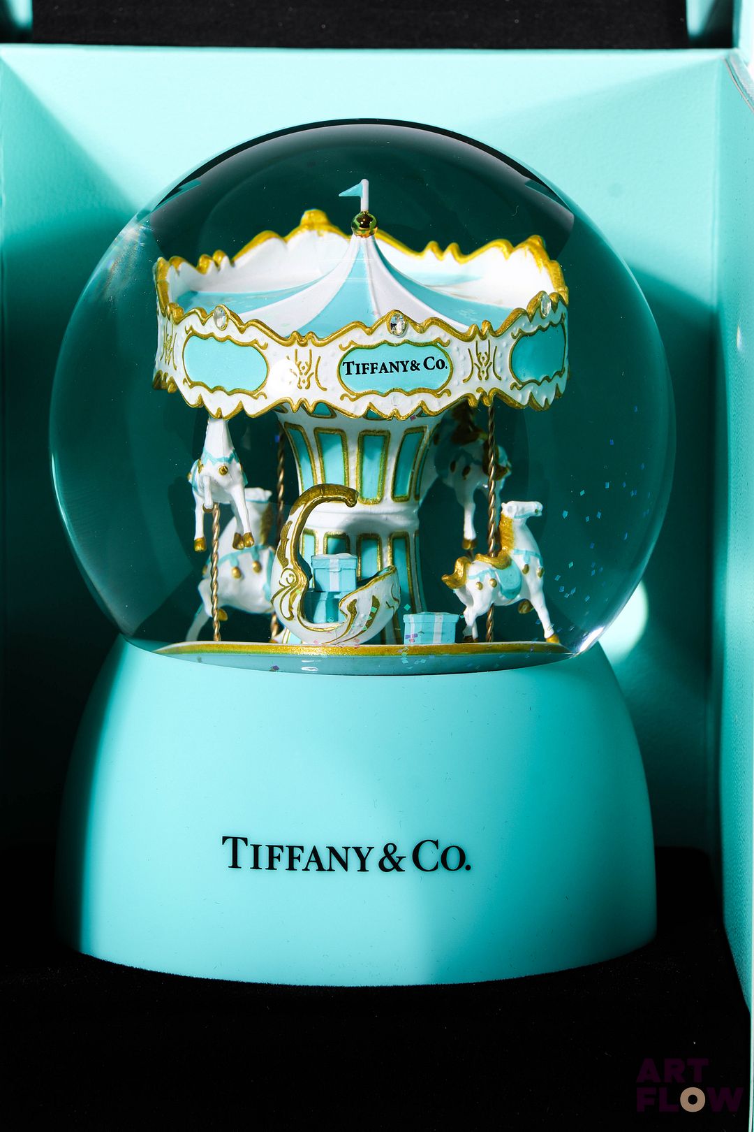 TIFFANY & CO Boule à neige faisant office de boîte à musique. L'intérieur figurant un caroussel. Édition limitée. Fonctionnelle. H. 15 cm. Dans son coffret d'origine Très bon état général