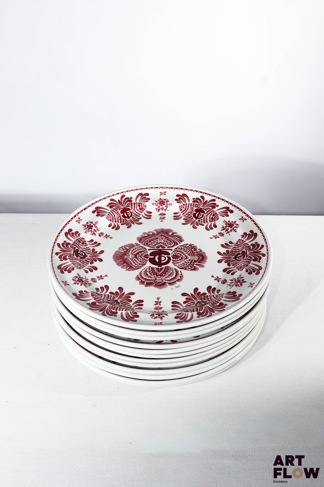 SARREGGUEMINES Décor de G. Paoli et assiettes provenant du restaurant gastronomique Les Frères Troisgros situé à Roanne en région Rhône Alpes Douze assiettes en porcelaine pyroblan à motifs dans les tons bordeaux D. 28,5 cm Très bon état général malgré quelques très légers défauts (bulles, petites égrenures, petites rayures d'usage et petites traces)