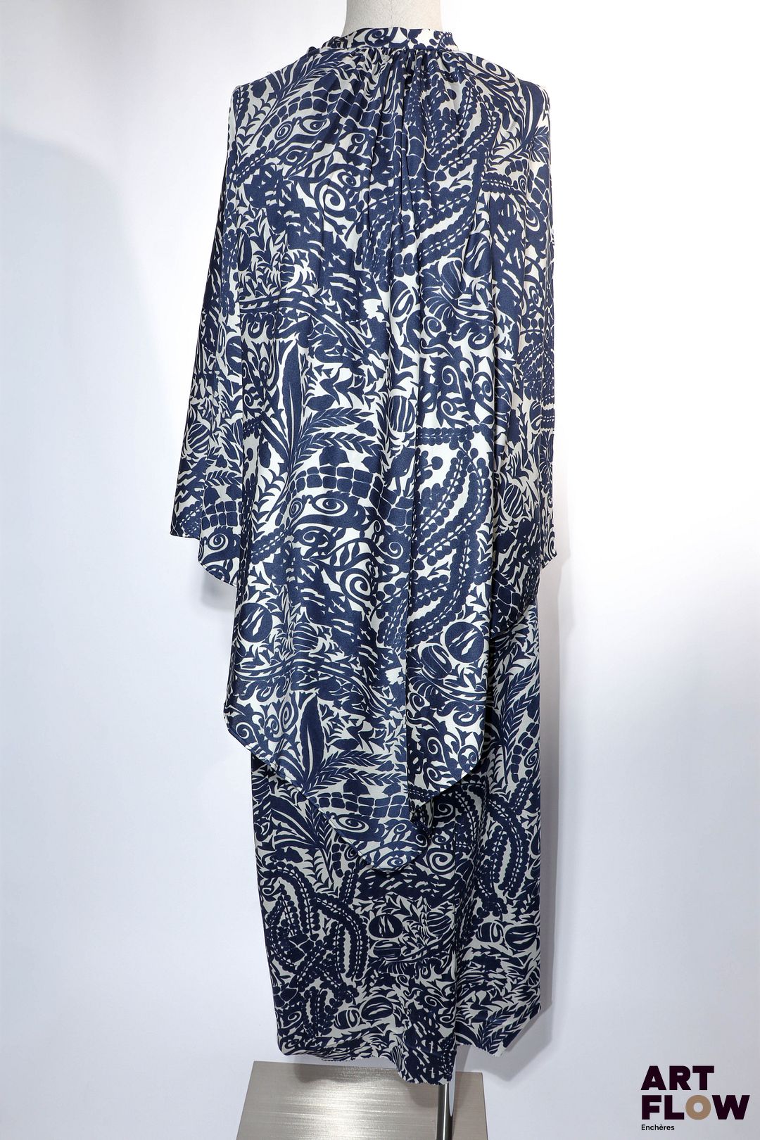 BALMAIN Provenance : Madame Geneviève de Gaulle Anthonioz, entrée au Panthéon en 2015 Robe longue en jersey blanc à motif floral et végétal dans les tons bleu marine, effet deux pièces par une cape sans manche fendue en pointe sur une jupe longue. Circa 1969 Rehaussée de la rosette de la Légion d'honneur Taille présumée 36/38 Bon état général malgré quelques légers défauts (petits fils tirés)