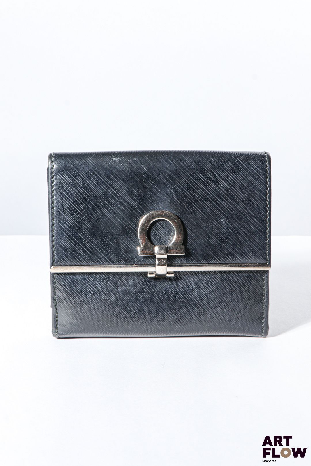 SALVATORE FERRAGAMO Porte feuille et monnaie en cuir noir, bijouterie en métal argenté, fermoir à pression et à rabat. Dimensions : 10 x 12 cm Bon état général (quelques marques d'usage)