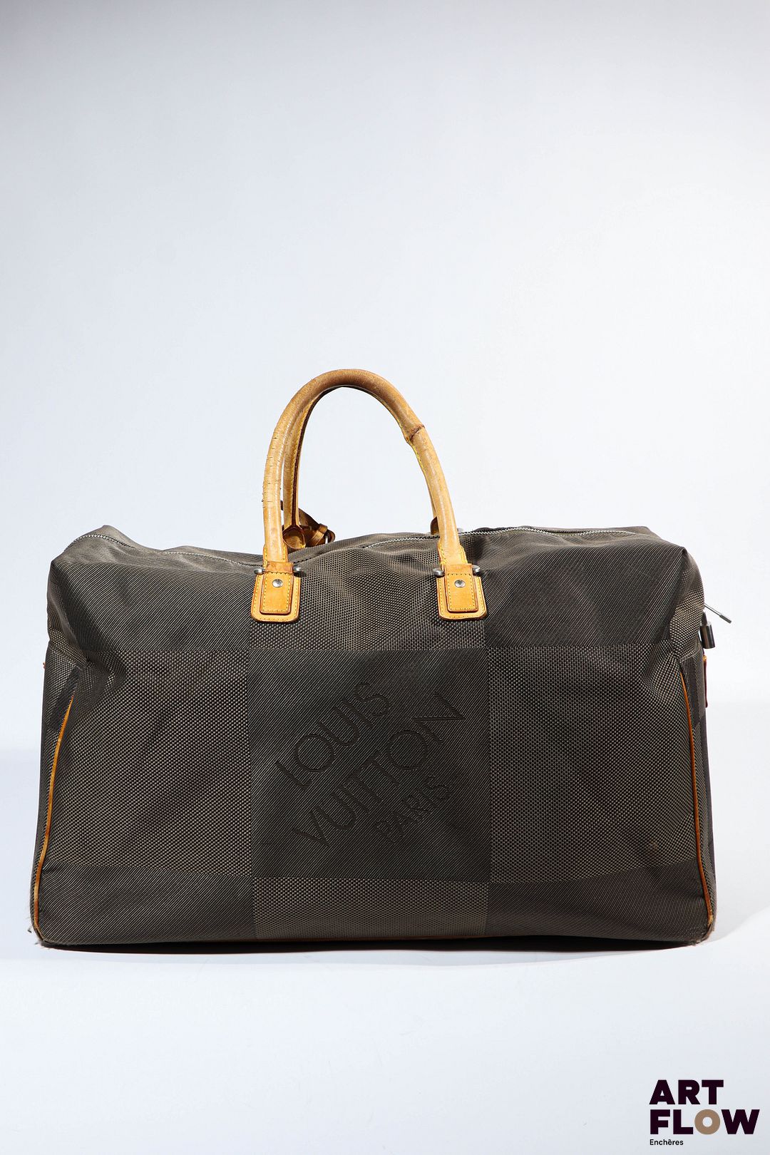 LOUIS VUITTON Paris Sac de voyage en toile damier et cuir naturel. Garniture en métal argenté. Fermeture zippée ornée d’un cadenas. Dim. anses non comprises : H. 35 x L. 56 cm x P.24 cm Usures d’usage notamment sur les parties en cuir, tâches.