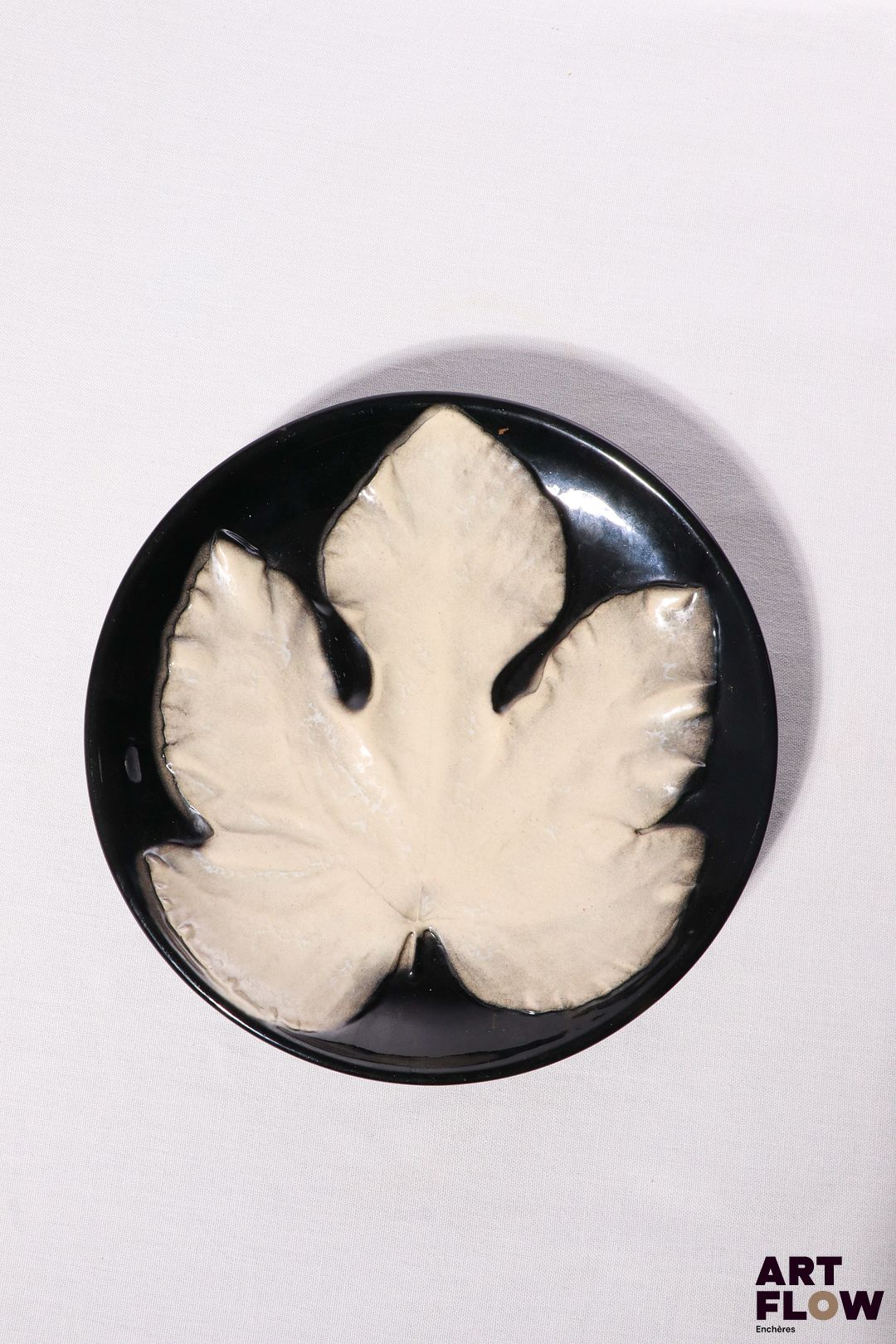 POL CHAMBOST (1906-1983) Assiette 864 "Feuille" en faience émaillée à couverte noire et blanche Tampon "864, Made in France" Diam. 23 cm Bibliographie : Philippe Chambost, "Pol Chambost, Sculpteur-Céramiste 1906-1983", Somogy Editions d'Art, Paris, 2006, modèle similaire p. 76