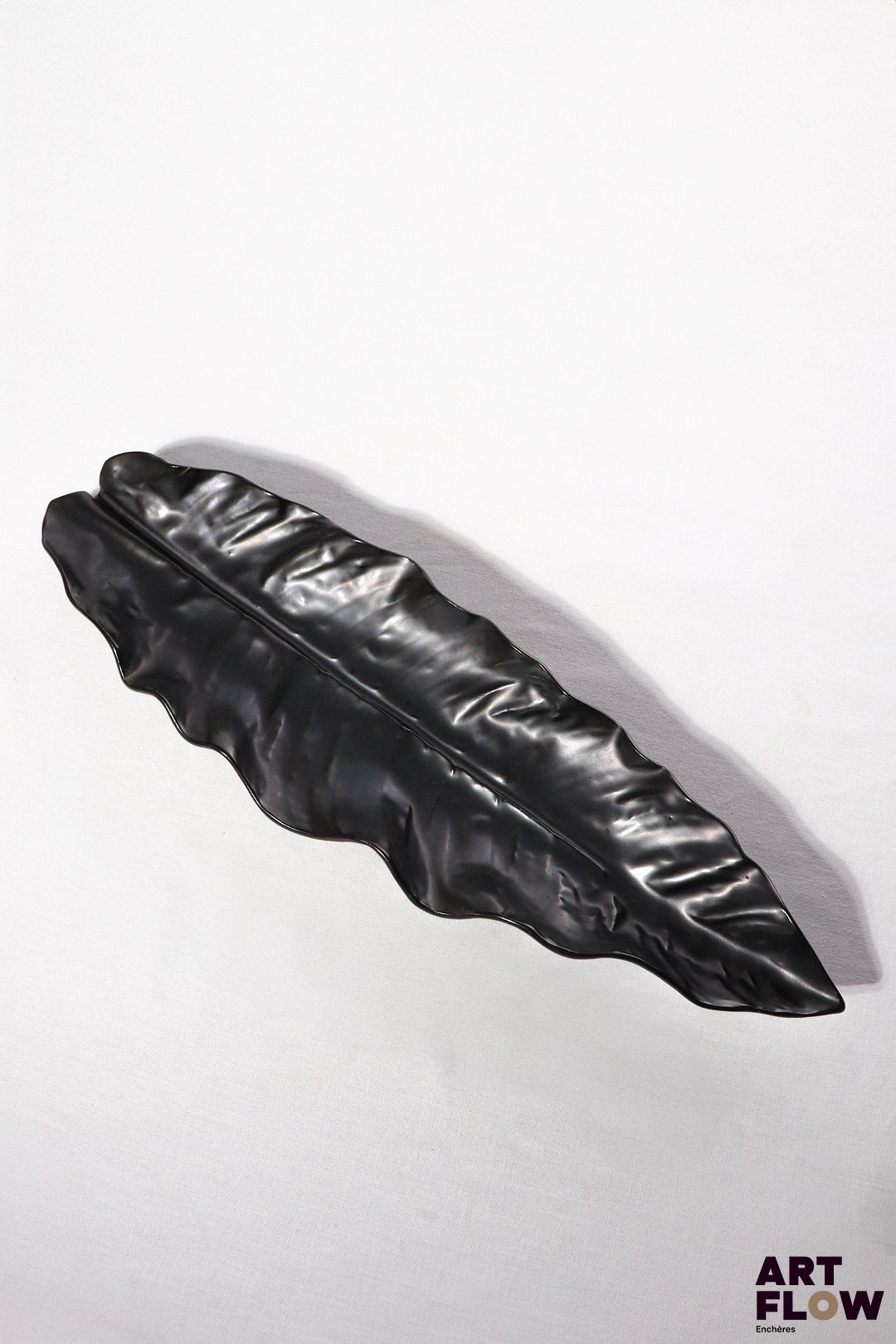 POL CHAMBOST (1906-1983) Importante coupe 21 "Feuille" en faience émaillée noire Incisée sous la base "Made in France" et tampon "21" 52 x 15 x 5 cm Bibliographie : Philippe Chambost, "Pol Chambost, Sculpteur-Céramiste 1906-1983", Somogy Editions d'Art, Paris, 2006, modèle similaire p. 125