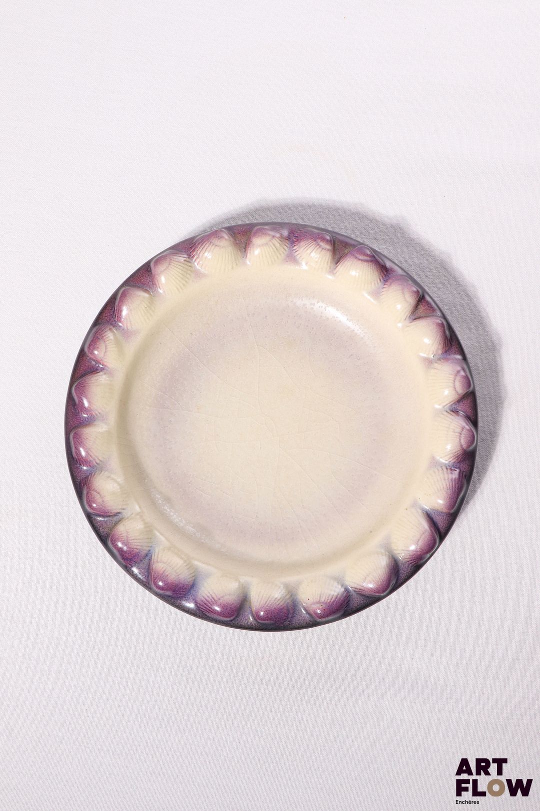 POL CHAMBOST (1906-1983) Plat 2106 "Coquillages" en faience émaillée à couverte polychrome dans les tons violets et blancs, l'aile ornée de coquillages. Incisé sous la base "2106, Poterie Pol Chambost, Made in France" D. 23,5, h. 4,5 cm