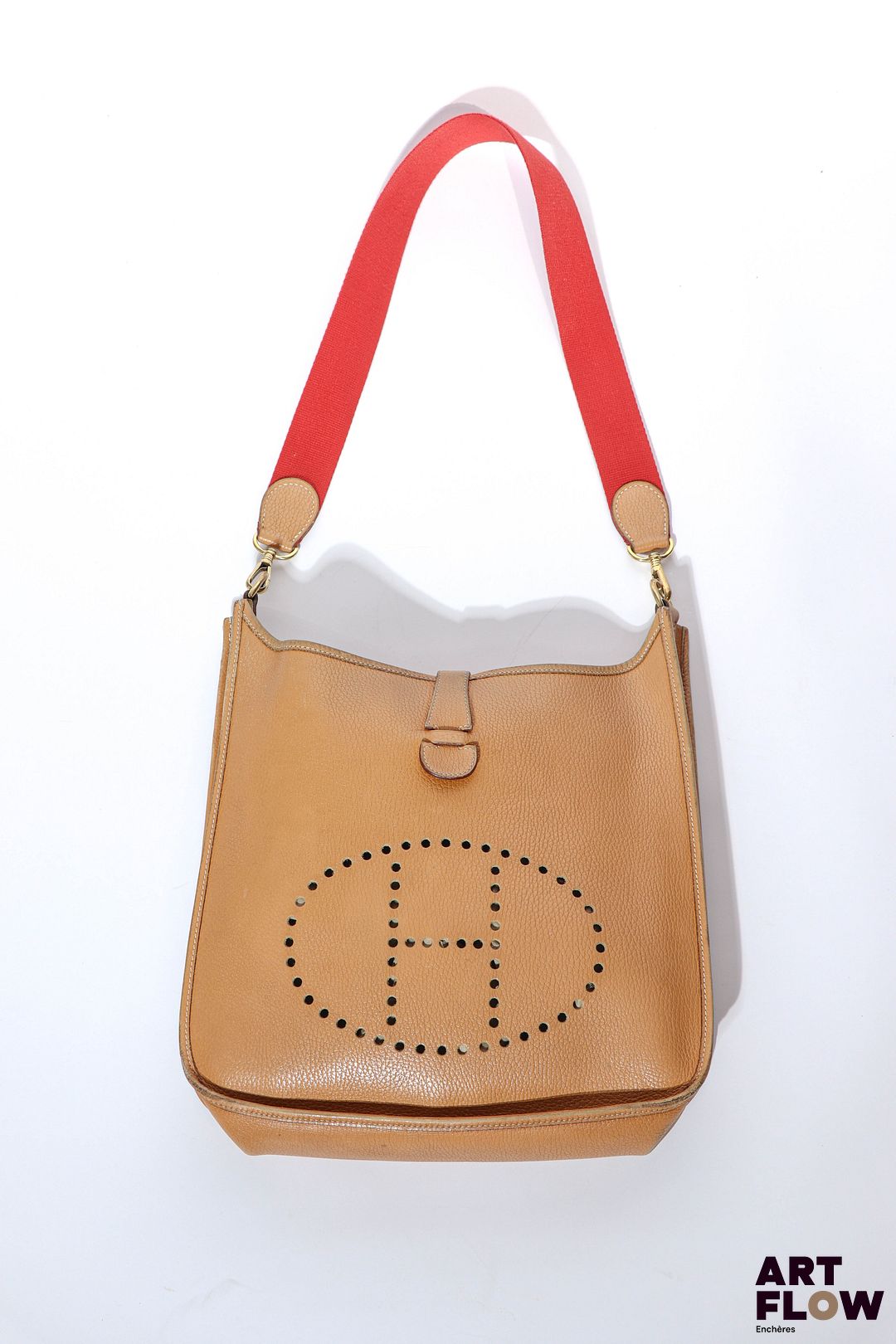 HERMÈS Evelyne 29 Vache Ardenne Gold, 1994 Cuir brun, agréments en métal doré, fermeture à pression, bandoulière en toile rouge 31 x 32,5 x 8,5 cm Bon état général malgré quelques usures (décoloration aux angles, taches à l'intérieur)